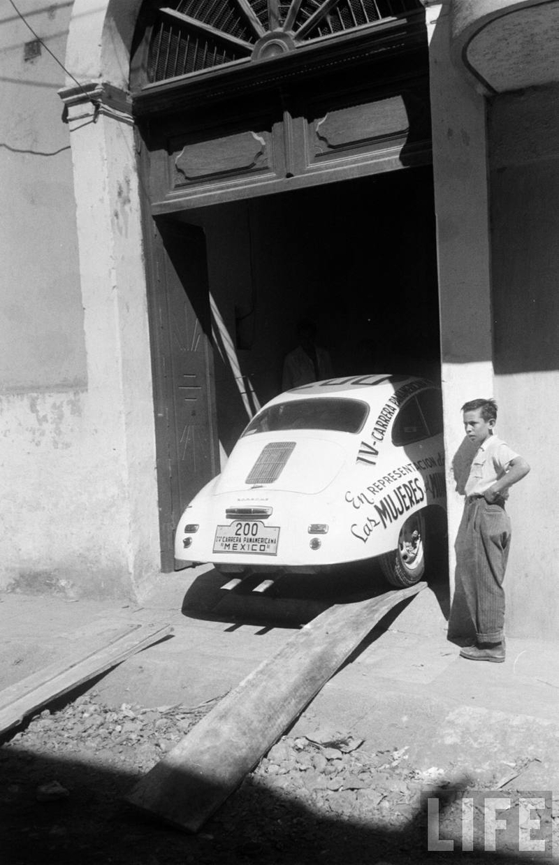 A boy standing next to a Porsche 356